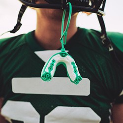 Dallas patient in football uniform with mouthguard hanging from helmet